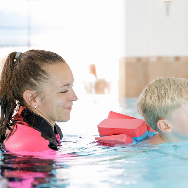 Frau mit Kind im Pool bei einem Kinderschwimmkurs im Familotel Kaiserhof in Tirol