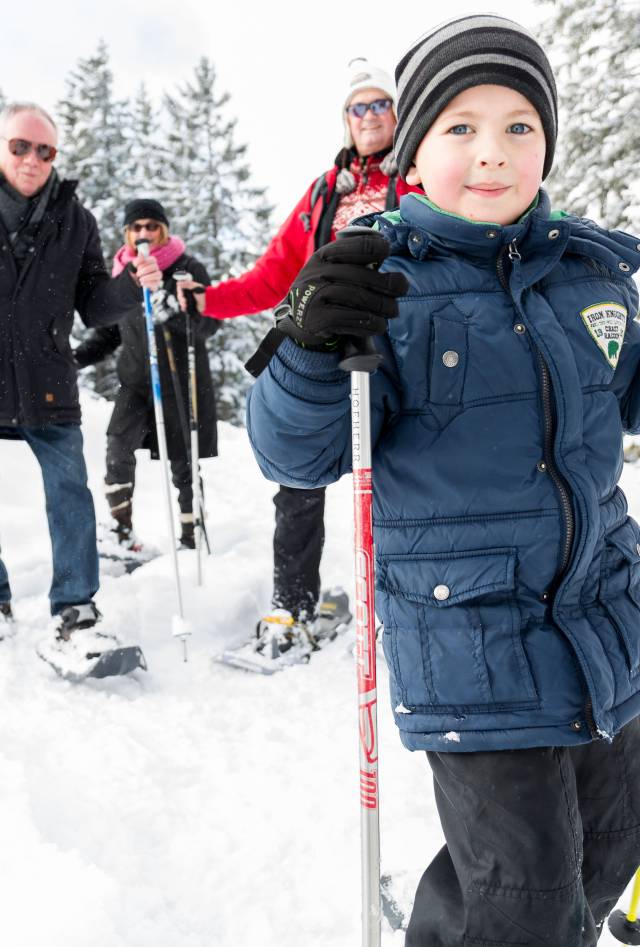 Familie mit Kind und Großerltern beim Schneeschuhwandern in Tirol