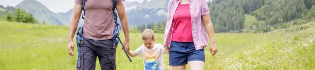 Parents with son hike across meadow in Berwang