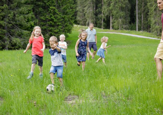 Kinder spielen auf grüner Wiese Fußball