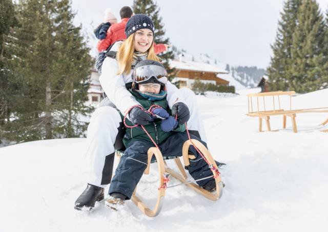 Mama mit Sohn auf Schlitten am Rodelhang in Bergwang
