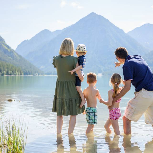 Eltern mit Kindern stehen im See in Berwang