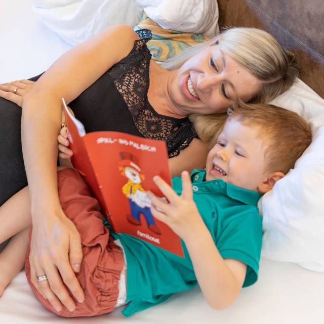 Mutter mit Sohn im Bett beim Buch lesen