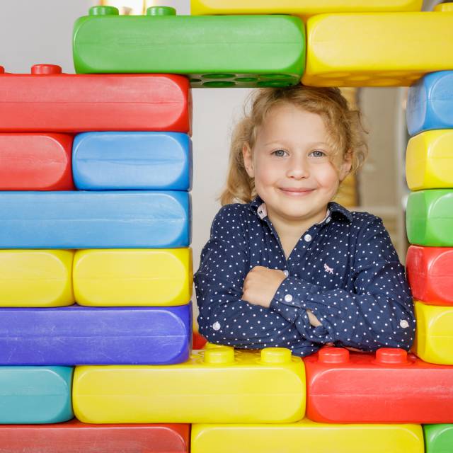 Child looks through large Lego wall