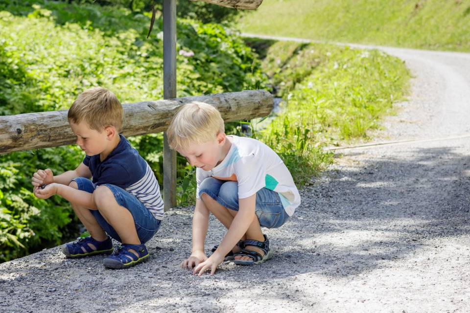 Two boys collecting stones on a bridge in Tyrol