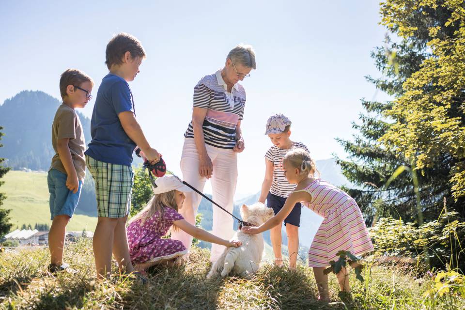 Children Petting a Dog and Holding it on a Leash