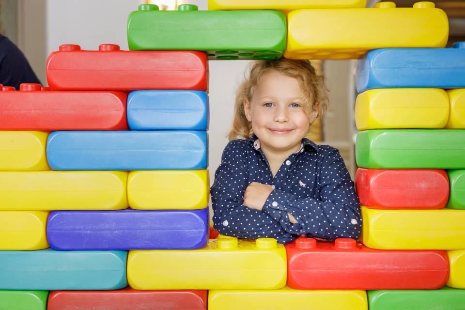 Child looks through large Lego wall