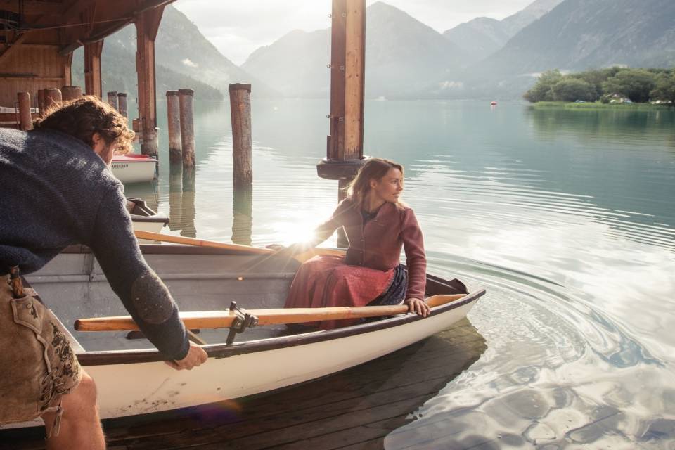 Zwei Erwachsene rudern über den Heiterwanger See mit dem Boot.