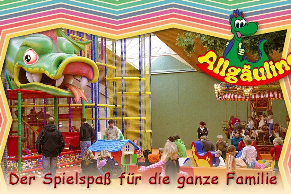 Allgäulino Familien-Erlebniswelt: bunte Indoor-Spielanlage mit großem grünen Drachenkopf als Rutsche, buntem Ballpool, Karussell und spielenden Kindern – Werbung mit Schriftzug ‚Der Spielspaß für die ganze Familie