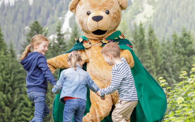 Familotel Kaiserhof Maskottchen spielt mit Kindern auf einer Wiese