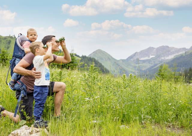 Familie schaut durch Ferngläser auf die Tiroler Alpen