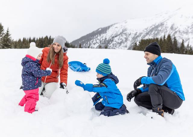 Familie baut einen Schneemann in Tirol