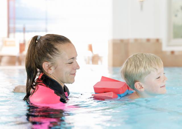 Frau mit Kind im Pool bei einem Kinderschwimmkurs im Familotel Kaiserhof in Tirol