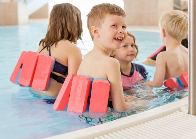 Kinder mit Schwimmhilfen im Wasser des Familotel Kaiserhof in Tirol