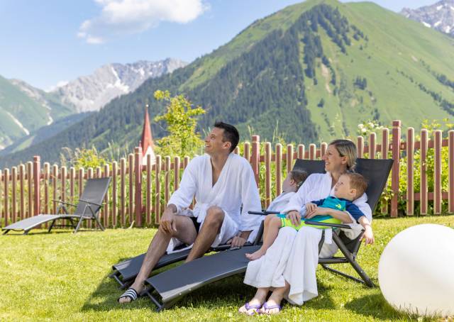Eltern entspannen auf Liegen auf der Wiese mit Blick auf die Tiroler Alpen