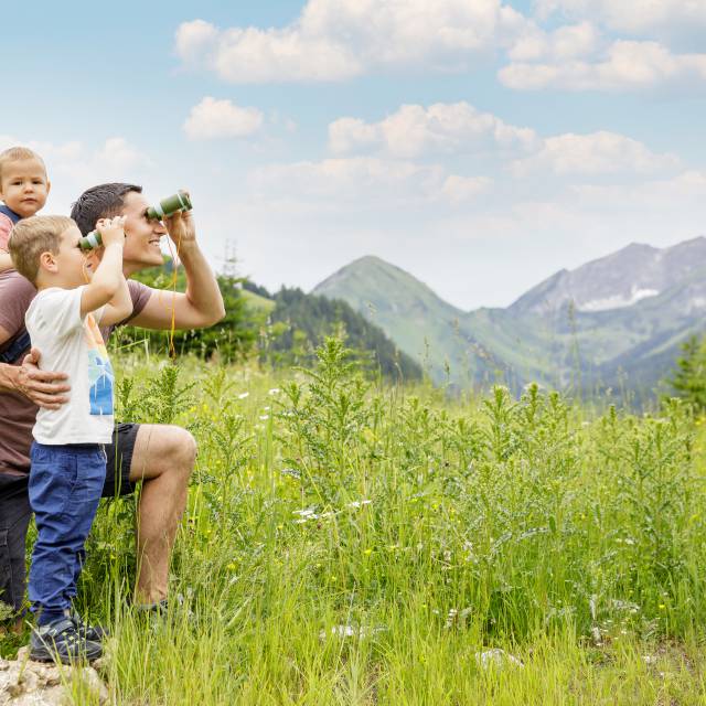 Familie schaut durch Ferngläser auf die Tiroler Alpen