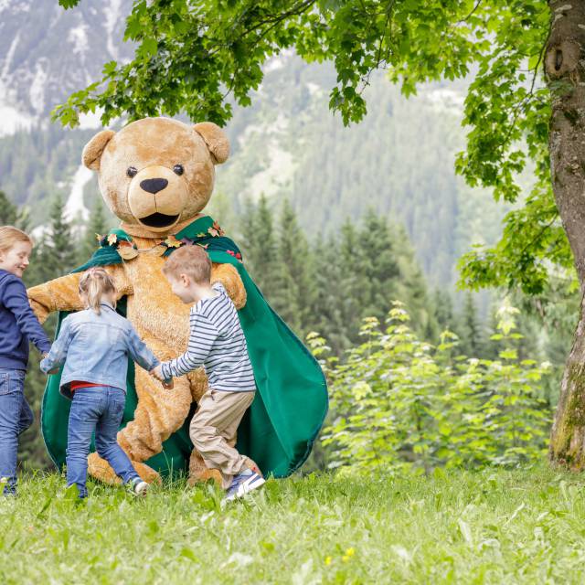 Familotel Kaiserhof Maskottchen spielt mit Kindern auf einer Wiese