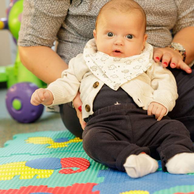 Baby sitzt auf Spieldecke