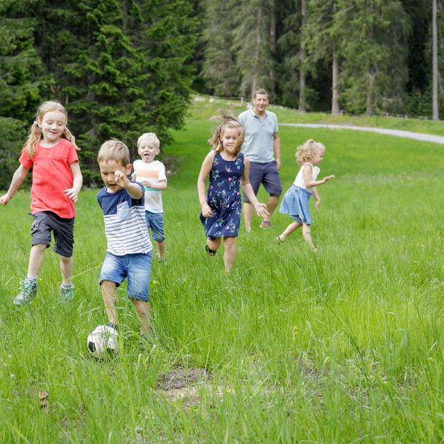 Kinder spielen auf grüner Wiese Fußball