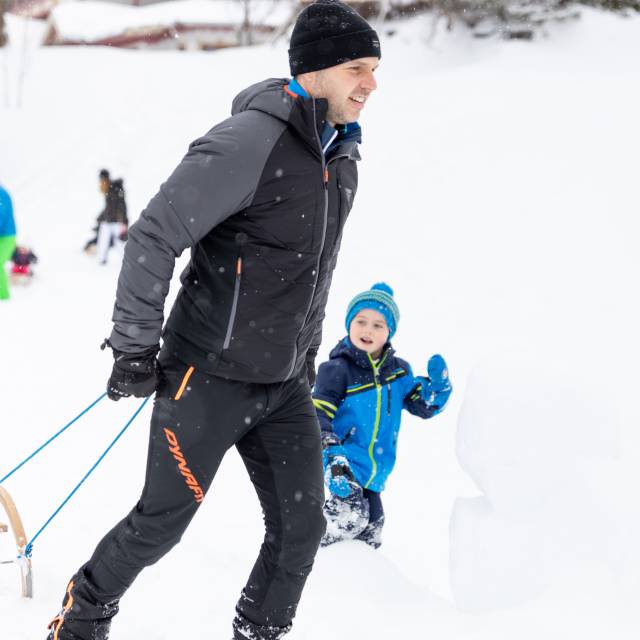 Eltern und Kinder spielen im Schnee in Berwang