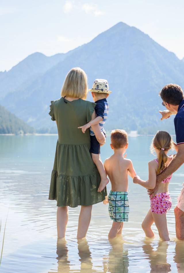 Eltern mit Kindern stehen im See in Berwang