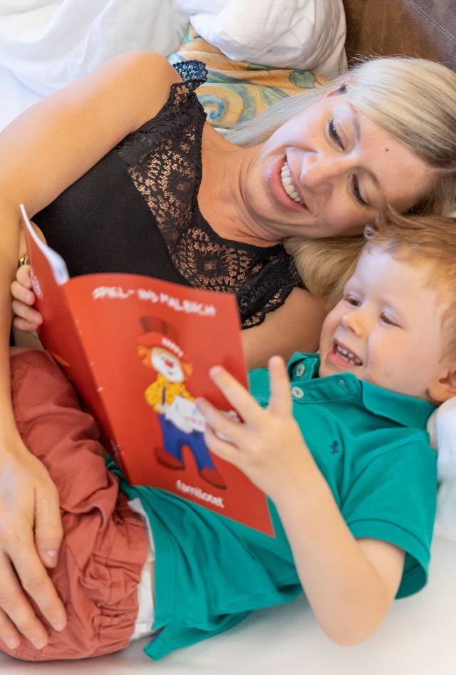 Mutter mit Sohn im Bett beim Buch lesen