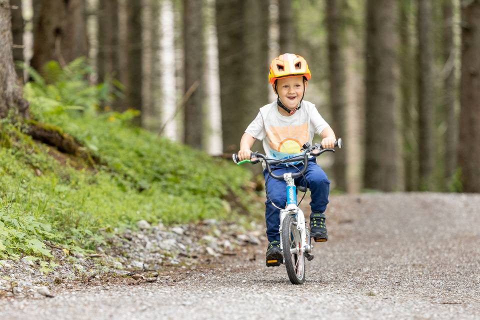 Junge fährt im Wald auf seinem Kinderrad