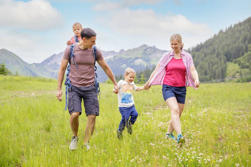 Familie läuft über Wiese in Tirol