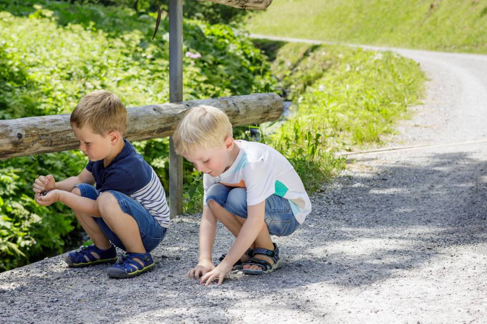 2 Jungs sammeln steine an einer Brücke in Tirol