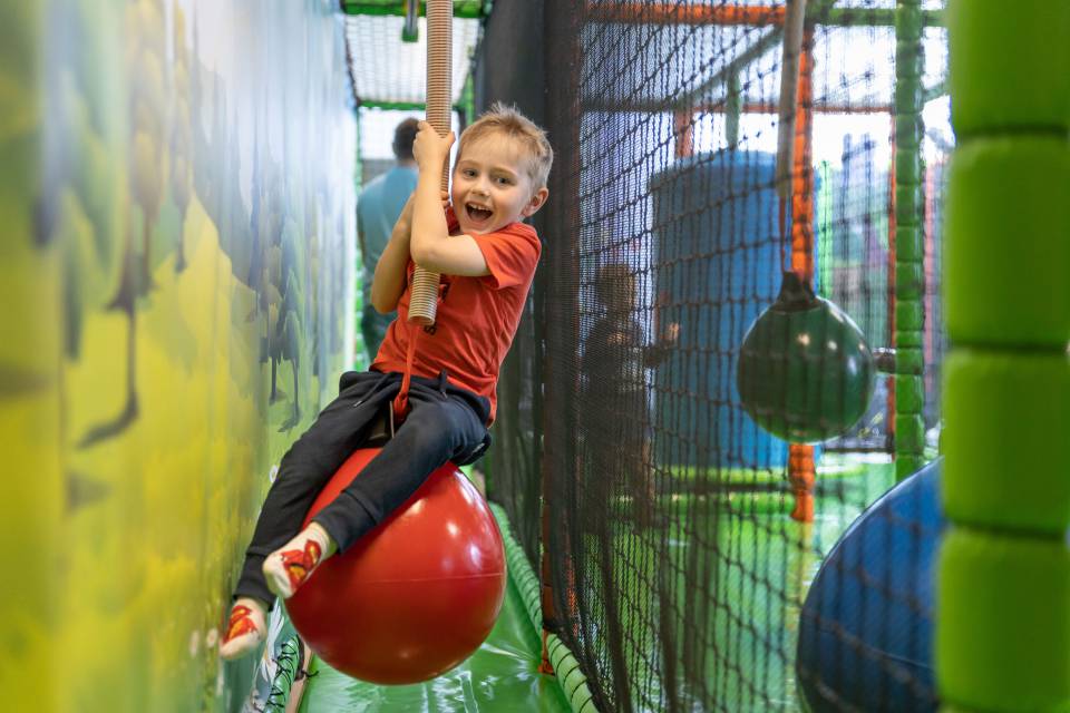 A child is swinging on a ball in the soft play area at Familotel Kaiserhof.