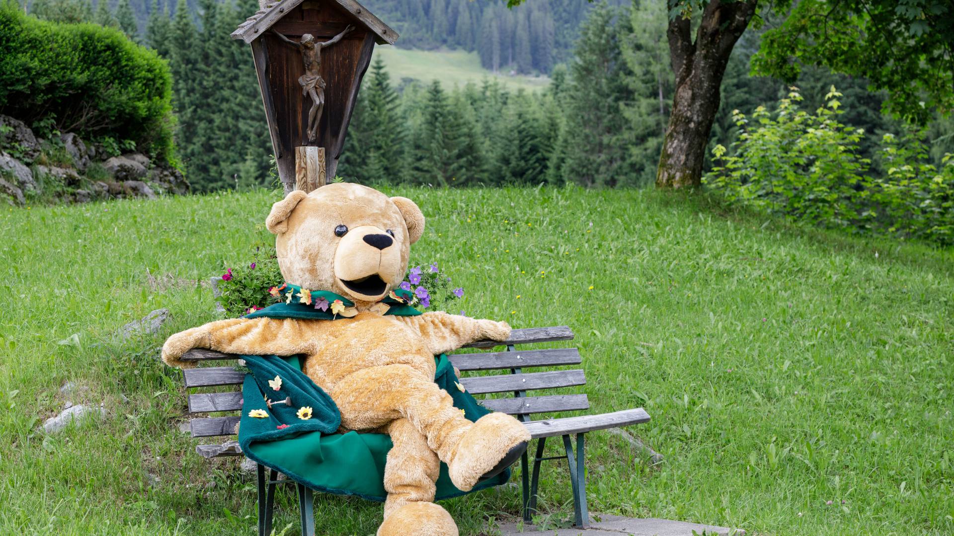 Familotel Kaiserhof Maskottchen Bärtram sitzt auf einer Bank