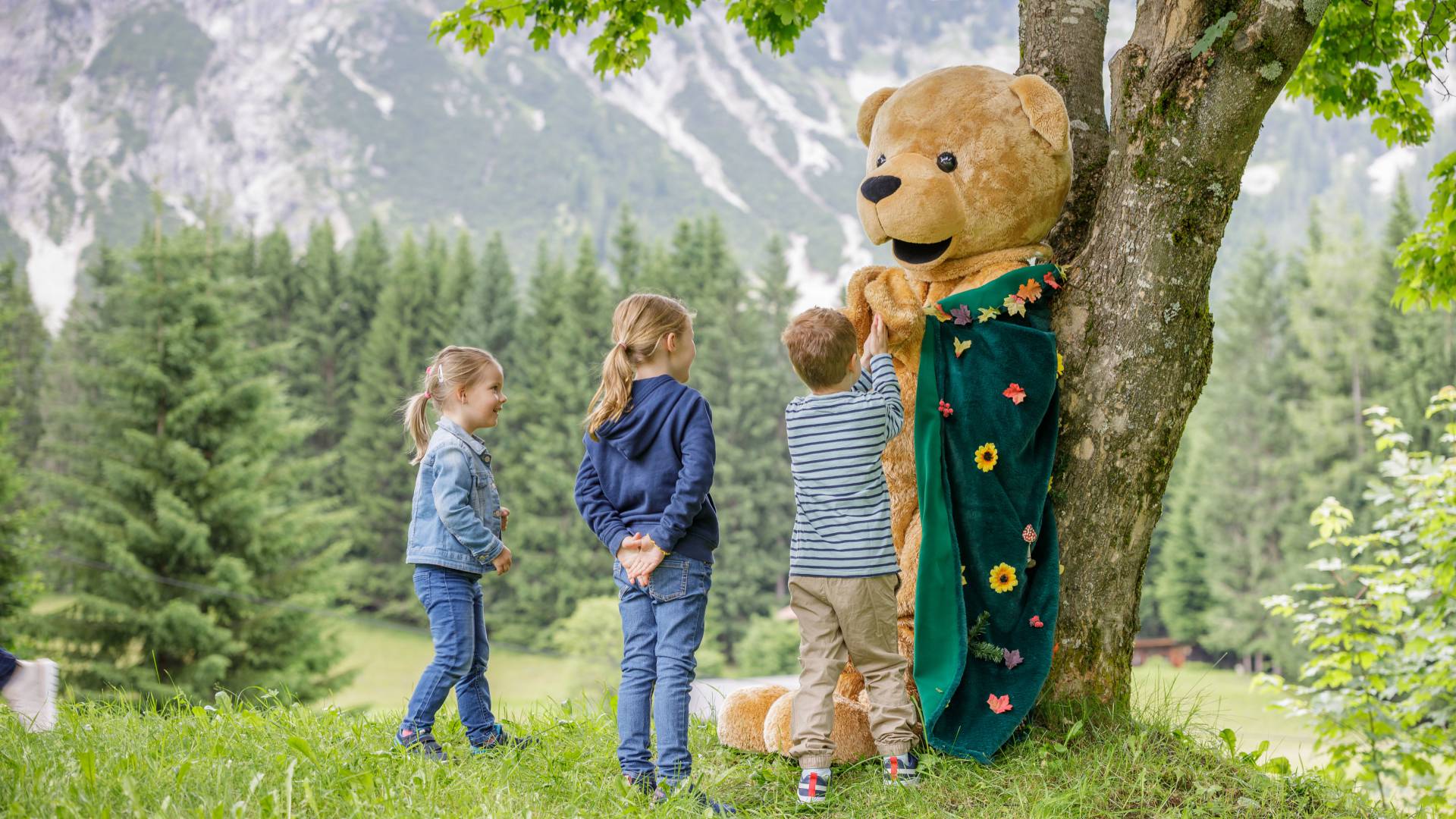 Familotel Kaiserhof Maskottchen Bärtram spielt mit Kindern auf Wiese