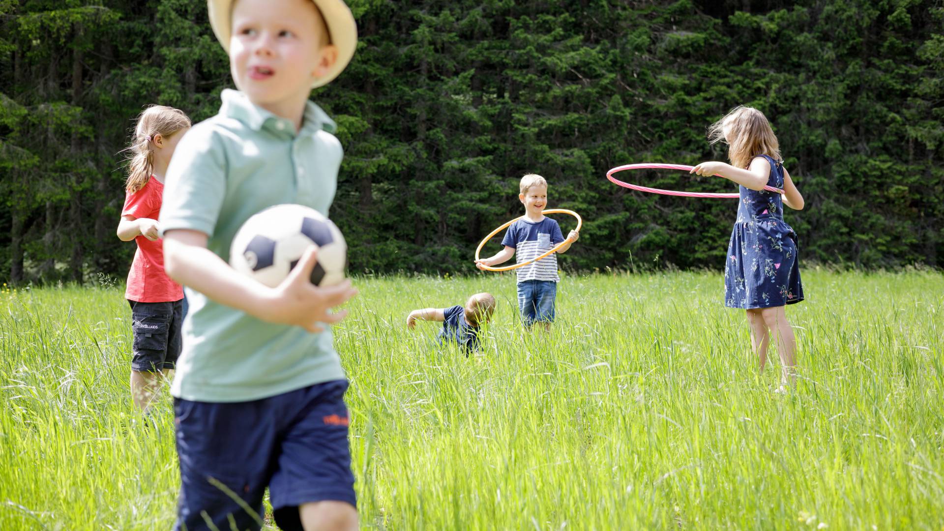 Kinder spielen auf Wiese in Tirol