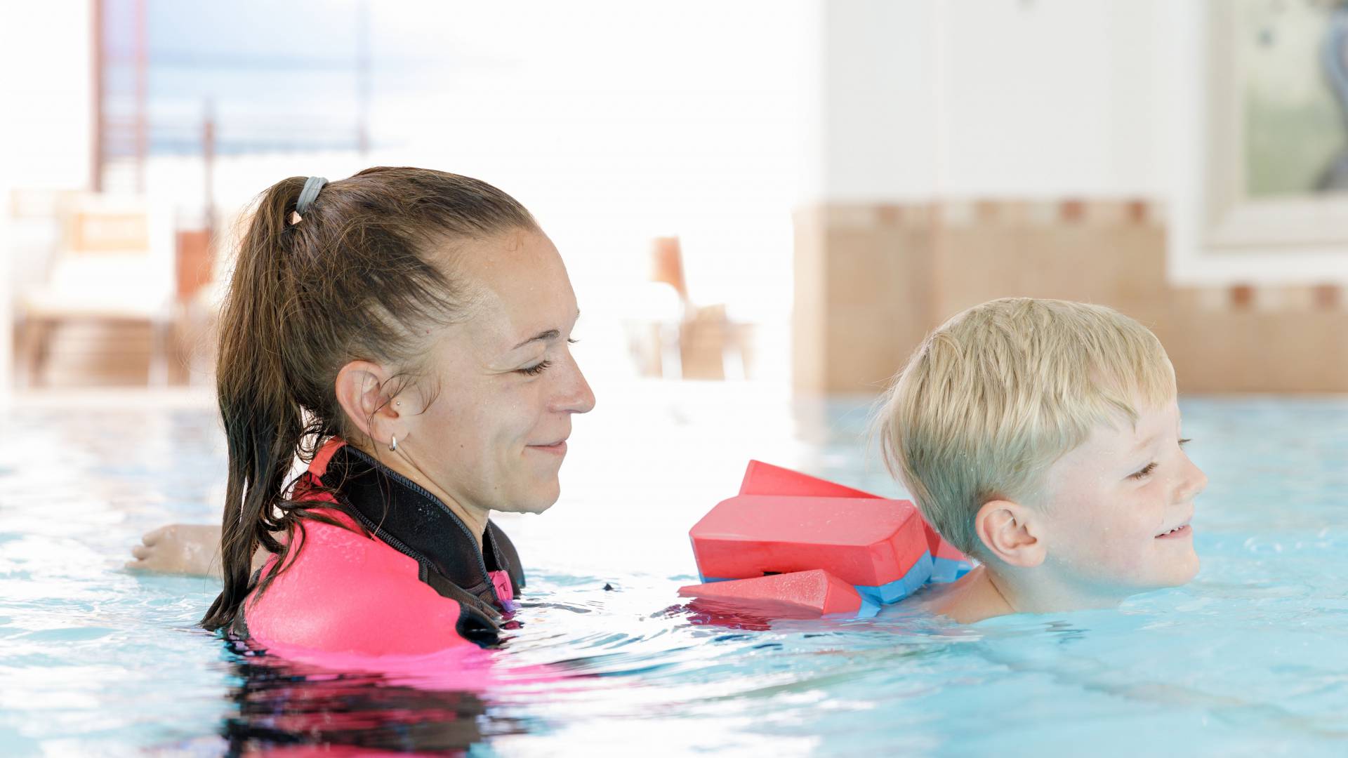 Frau mit Kind im Pool bei einem Kinderschwimmkurs im Familotel Kaiserhof in Tirol