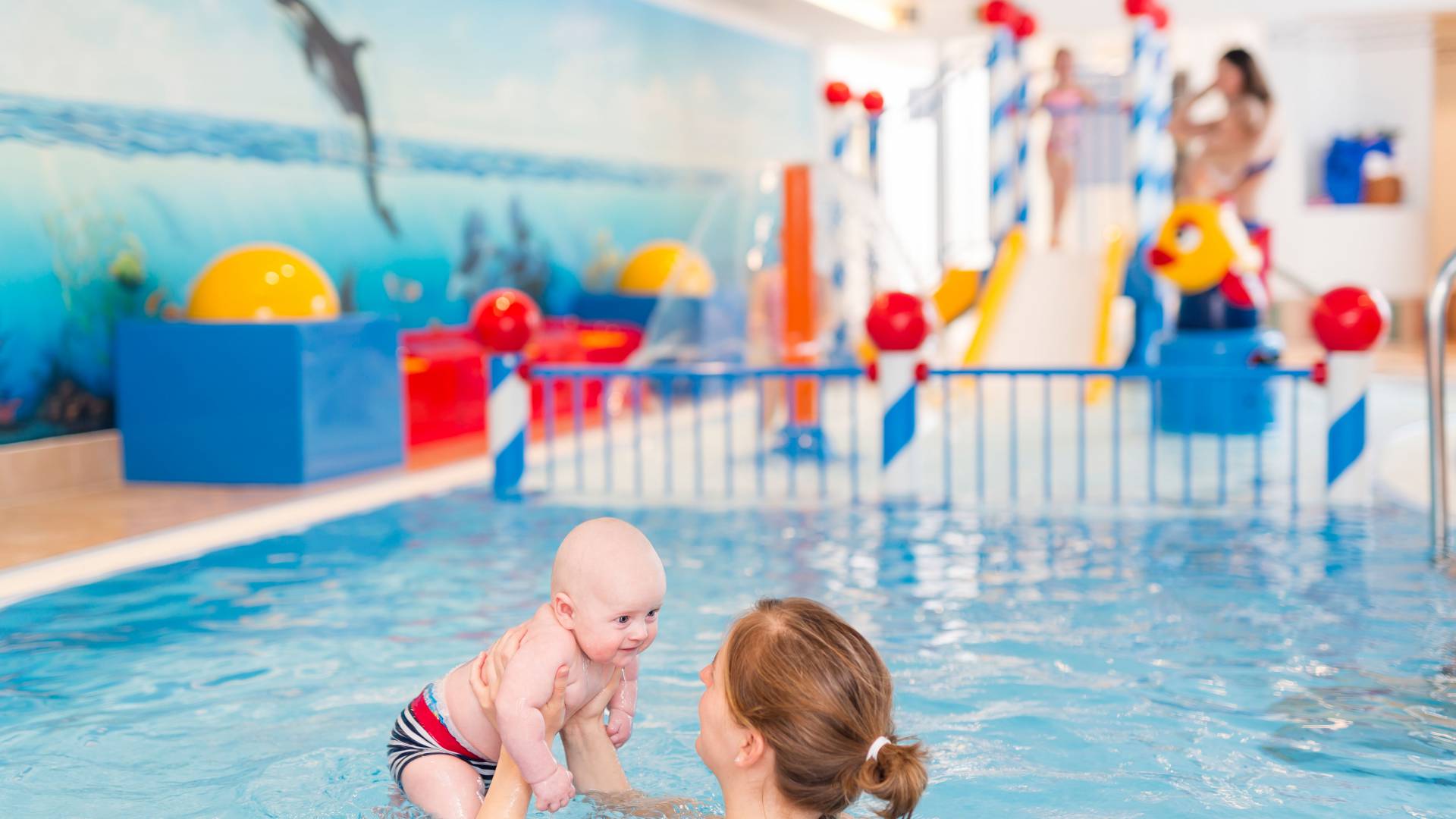 Eine Mutter entdeck mit ihrem Baby im Kinderbecken das Wasser.