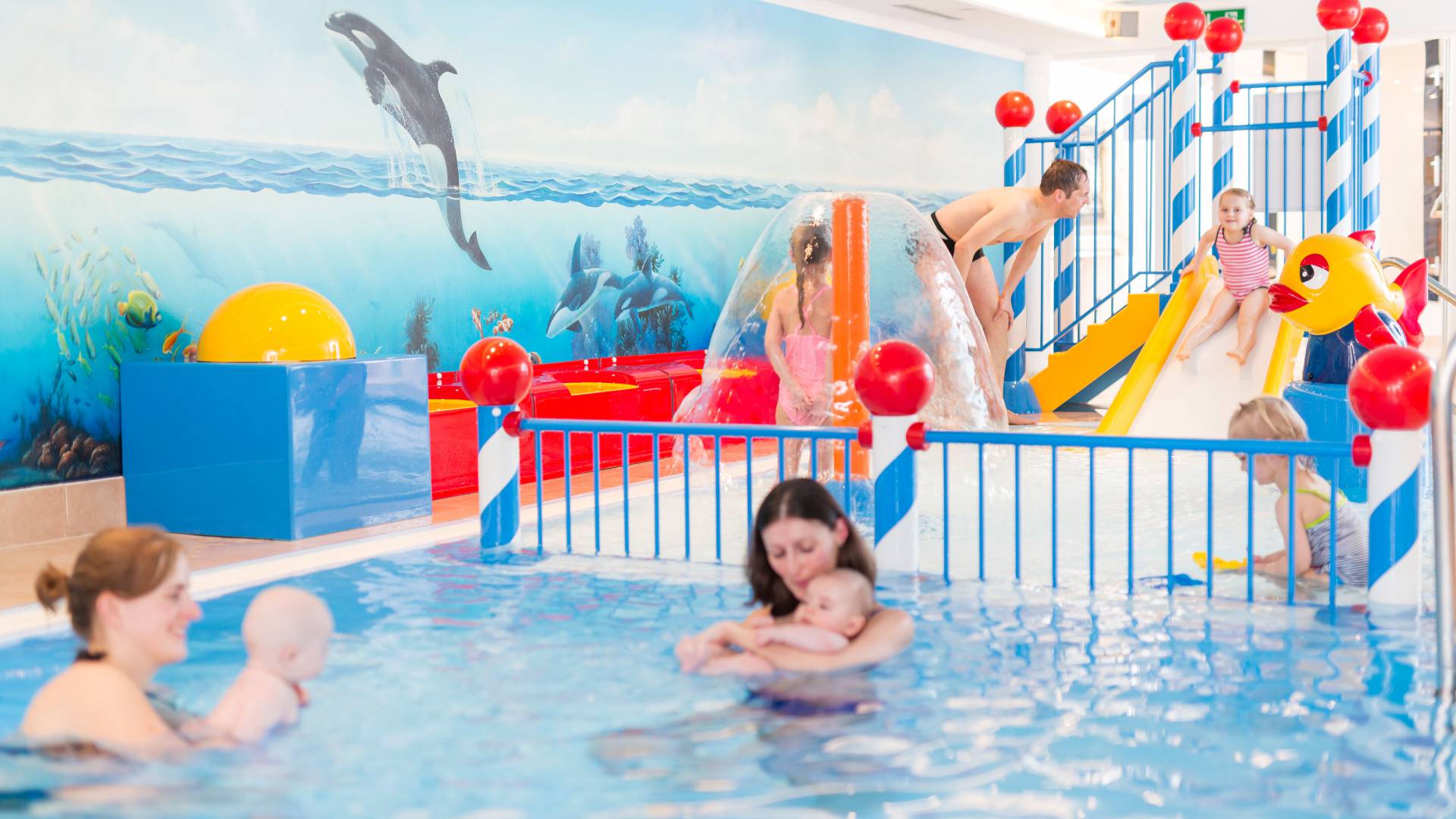 Eltern mit Kindern im Kinderschwimmbecken