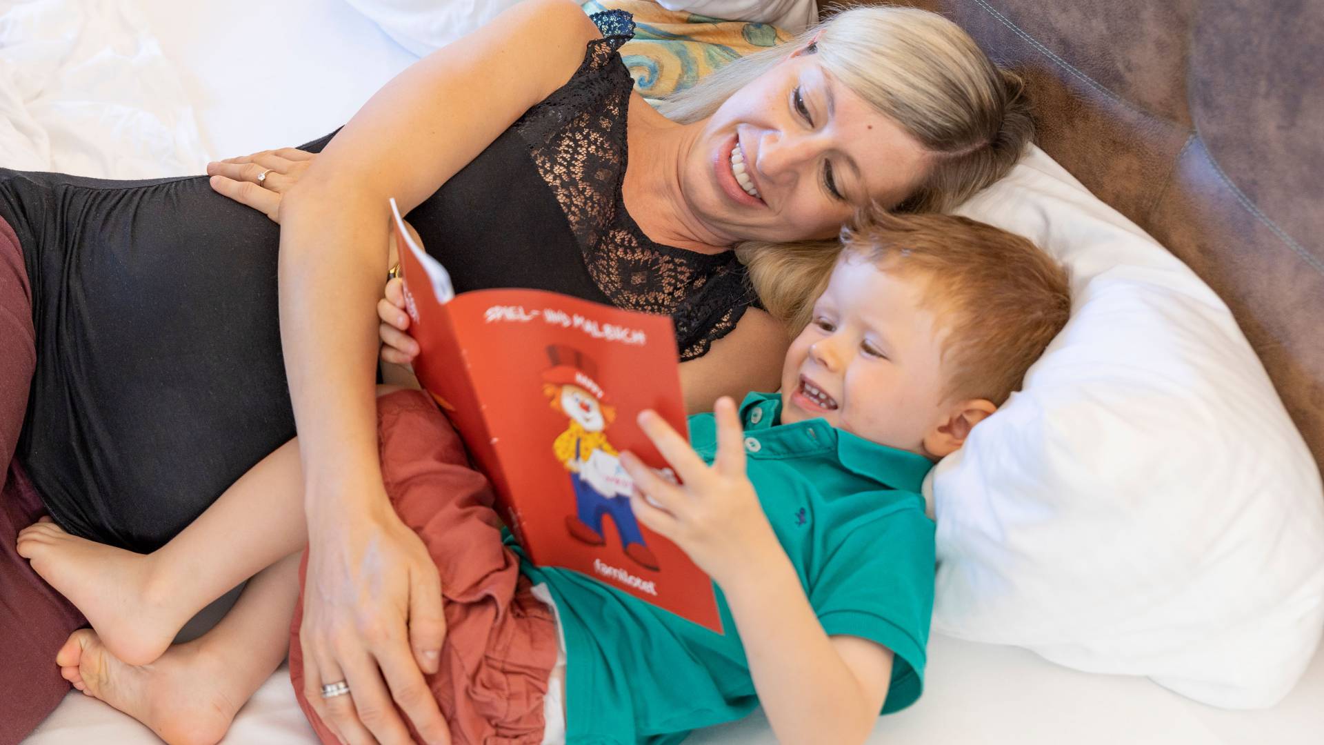 Mutter mit Sohn im Bett beim Buch lesen