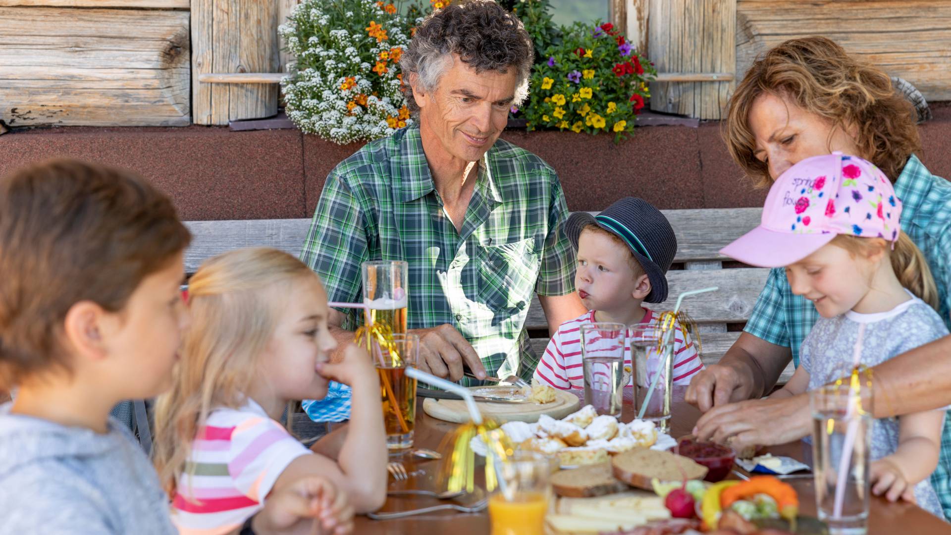 Kinder mit Großeltern essen auf einer Almhütte