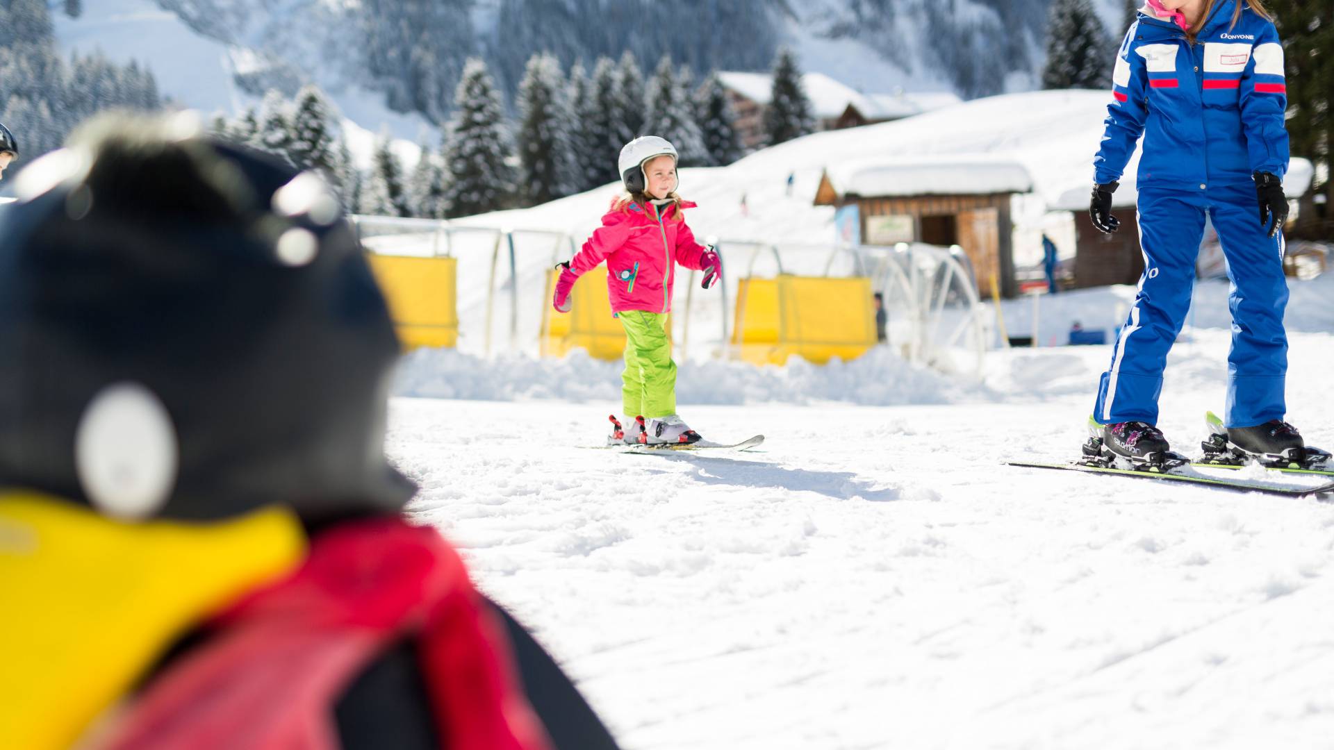 Kind in der Kinderskischule mit freundlichem Skilehrer